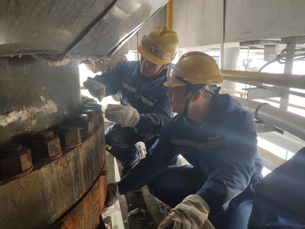 4月6日，機械修造部檢修二部張振華、盧超逸在檢修平臺處，進行4號氣化爐破渣機下降管短節(jié)法蘭螺栓的拆卸工作。.jpg