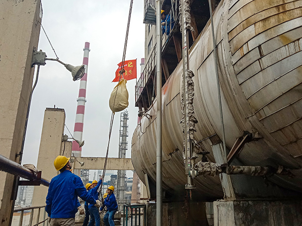 5月10日中午，在動(dòng)力車間三期工藝除氧器地面，黨員突擊隊(duì)隊(duì)員用滑輪往工藝除氧器平臺(tái)運(yùn)送鋼絲網(wǎng)，用以纏繞新填料.jpg